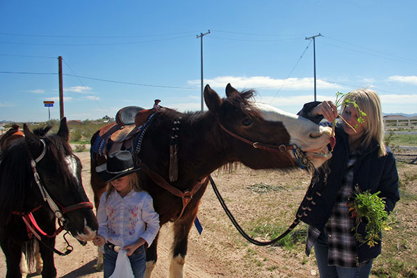 A young lady and her mother ride up on horses to Tonopah Rob’s Vegetable Stand in Tonopah, Arizona